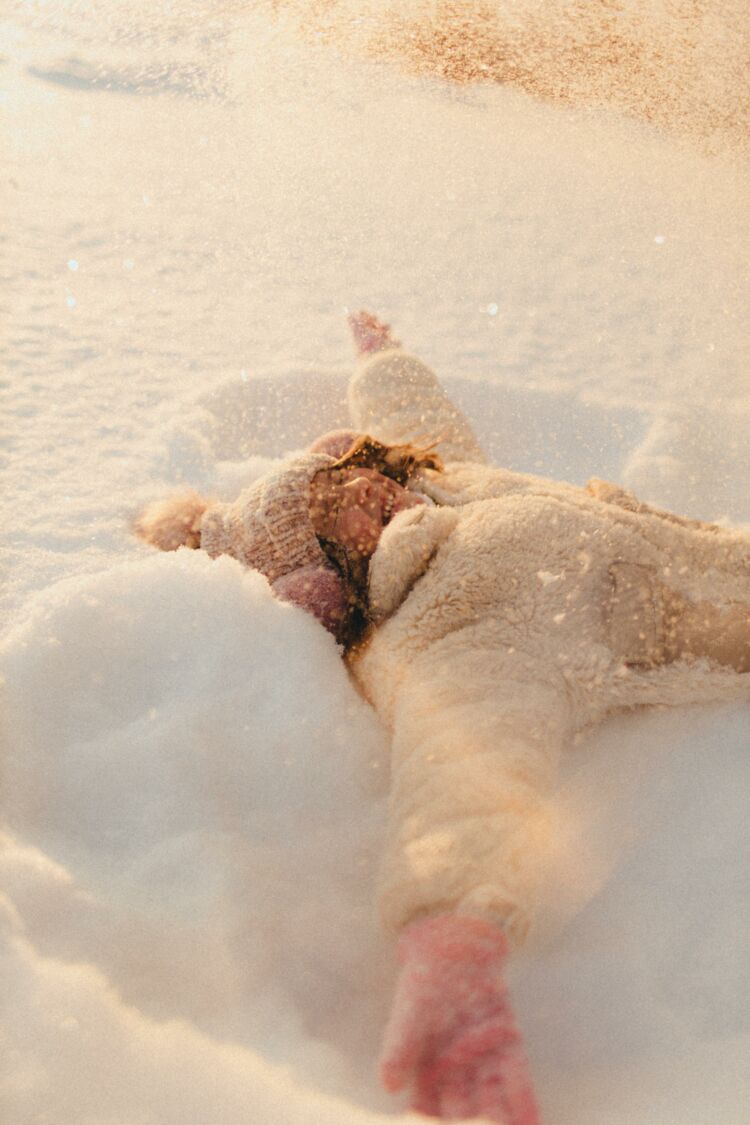 Tyttö makaa lumessa iloisesti lumienkeliä tehden