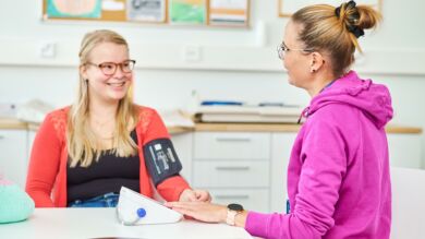 Terveydenhoitaja mittaa asiakkaan verenpainetta.