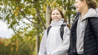 Kaksi koululaista kävelee hymyillen koulun pihalla.