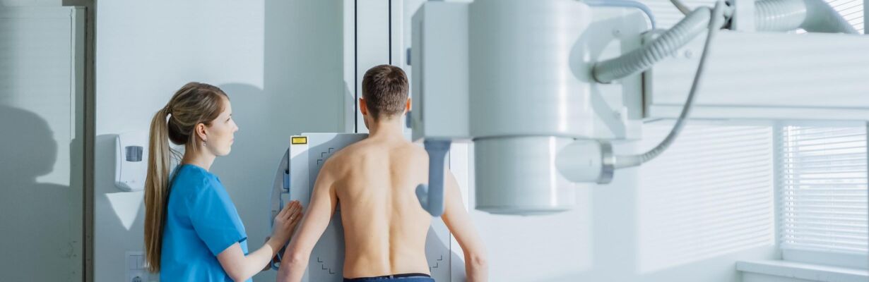Kuvassa röntgenhoitaja ja potilas valmistautuvat röntgentutkimukseen