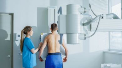 Kuvassa röntgenhoitaja ja potilas valmistautuvat röntgentutkimukseen