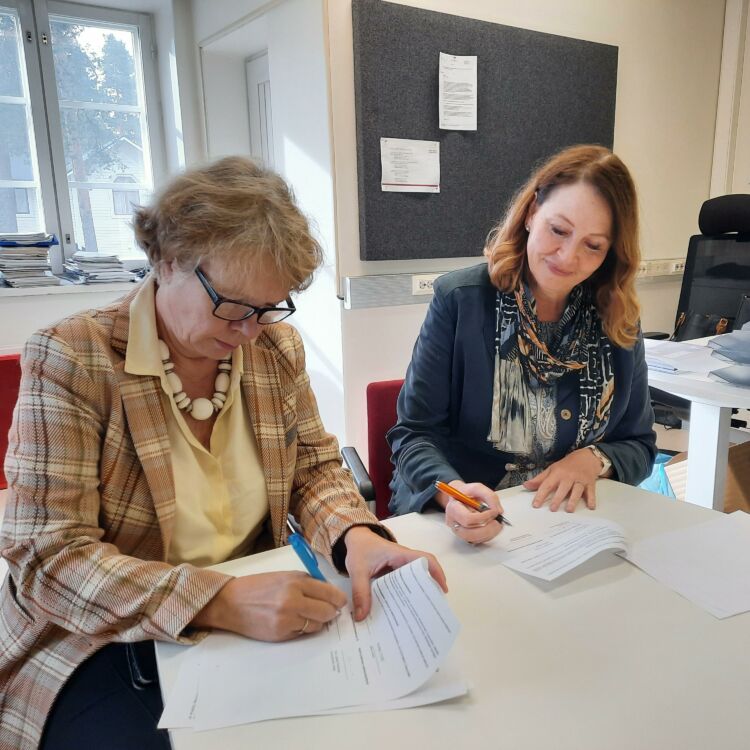 Pirjo Laitinen-Parkkonen ja Riitta Konkola allekirjoittavat sopimuksen.