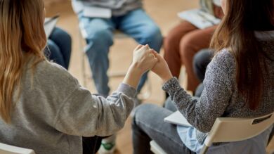 Kuvassa nuoria ringissä ryhmäterapiassa. Nuoret pitävät toisiaan kädestä kiinni.