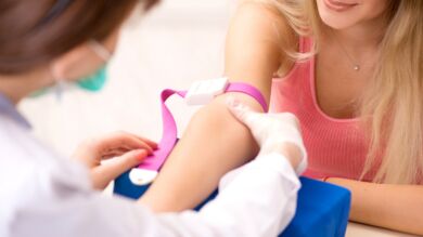 Kuvassa hoitaja ottaa verinäytettä laboratorion asiakkaalta, nuorelta naiselta.
