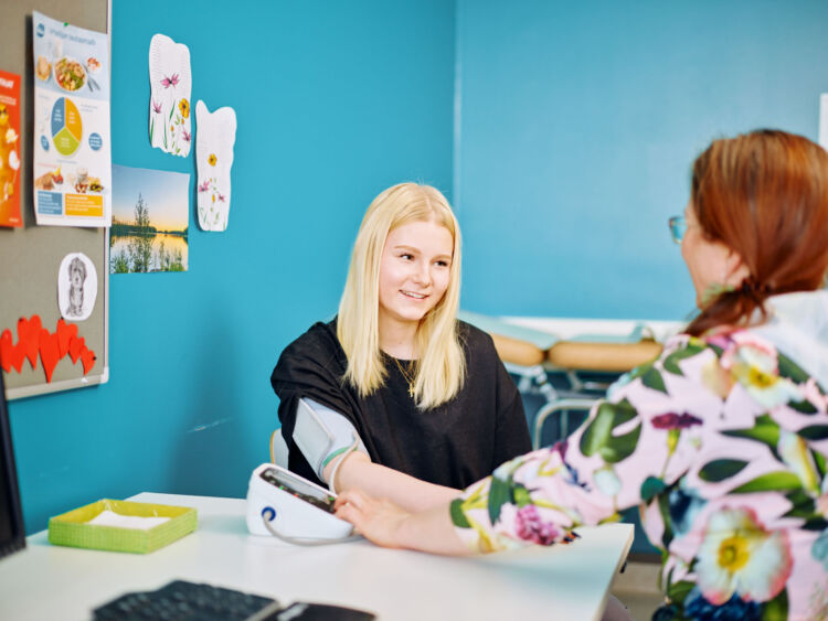 Kouluterveydenhoitaja mittaa nuorelta verenpaineen.