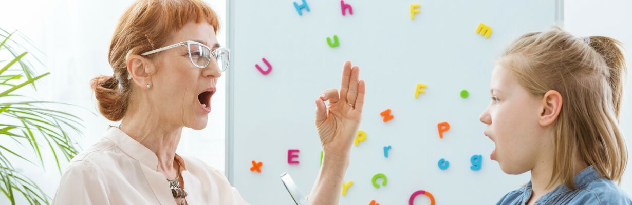 Vanhempi nainen antaa puheterapiaa nuorelle tytölle