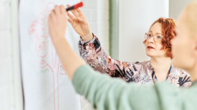 Kaksi sote-alan työntekijää kirjoittaa yhdessä taululle.