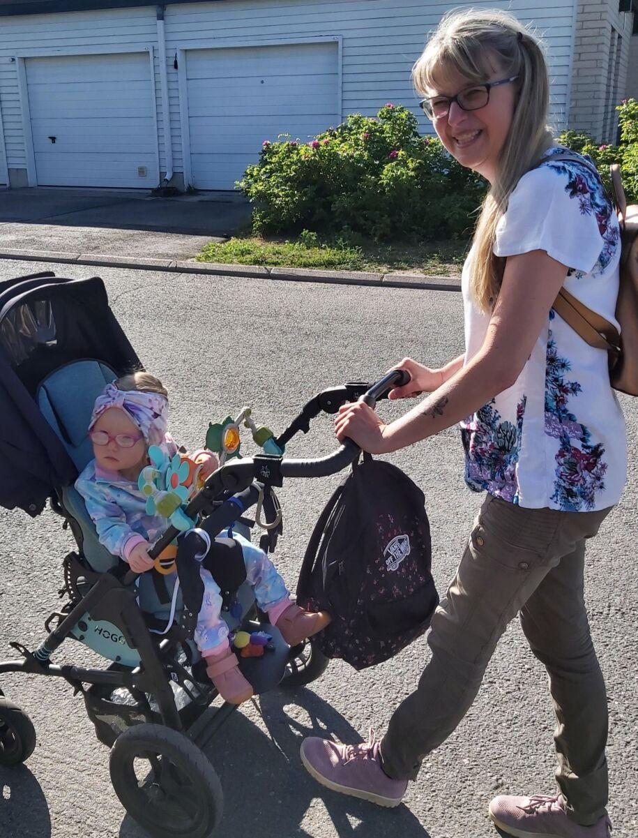Perhehoitaja Kristiina Haltia työntää lastenrattaita, joissa istuu lapsi.